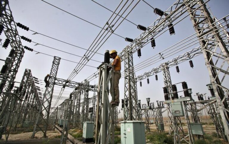 An employee works on electric pylons at a power station in Greater Noida